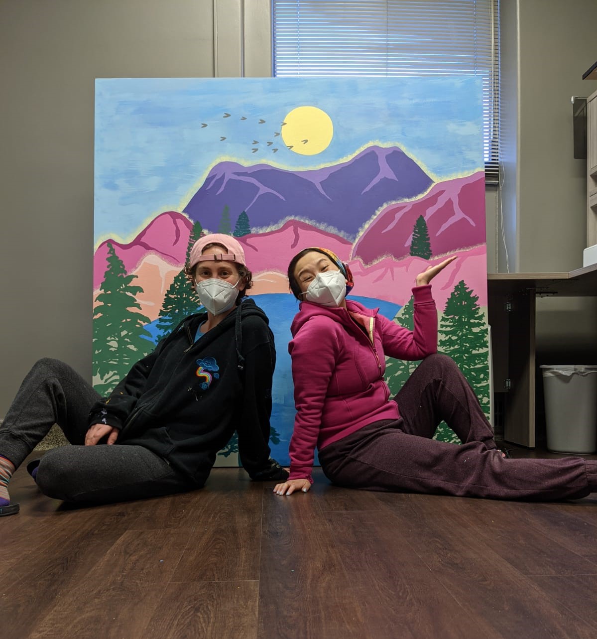 Bareket and Amanda sit in front of painted mural