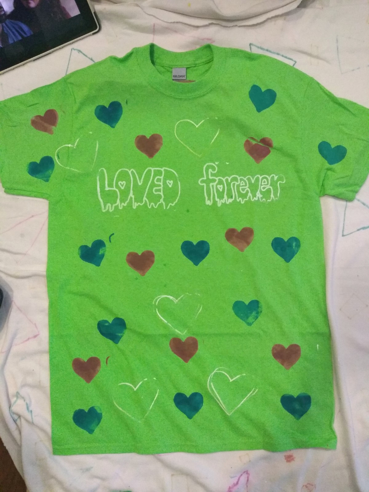 Green shirt lay flat with printed hearts with text, Loved forever