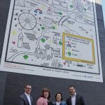 Four people standing in front of large black and white mural with spots of colour on black wall to celebrate mental health artwork in Toronto.