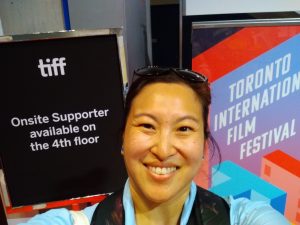 Amanda smiles between two signs from Toronto International Film Festival