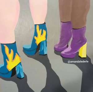 A pair of light skin legs wear blue heeled boots with fire painted on the side while dark skin pair of legs wears purple heeled boots with yellow heels.